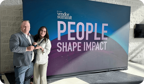 2 people standing in front of TD Synnex Vendor Summit banner.